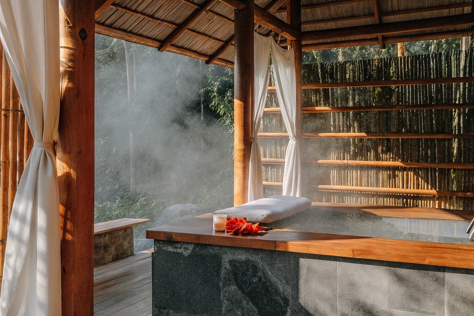 Therapist preparing botanical compresses in open-air spa pavilion
