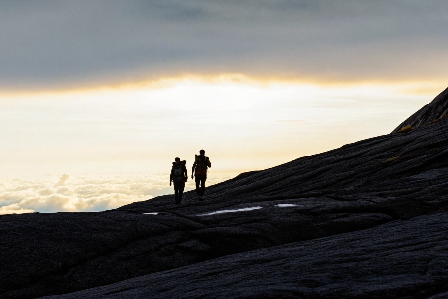 Climbers approaching Mount Kinabalu summit at sunrise