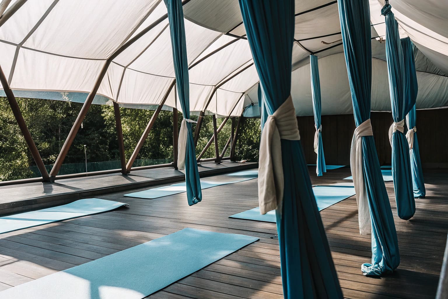 Guests practicing aerial yoga in open studio amongst forest canopy